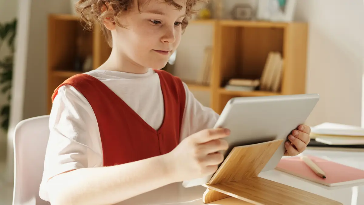 Garçon à son bureau devant une tablette posée dans un étui