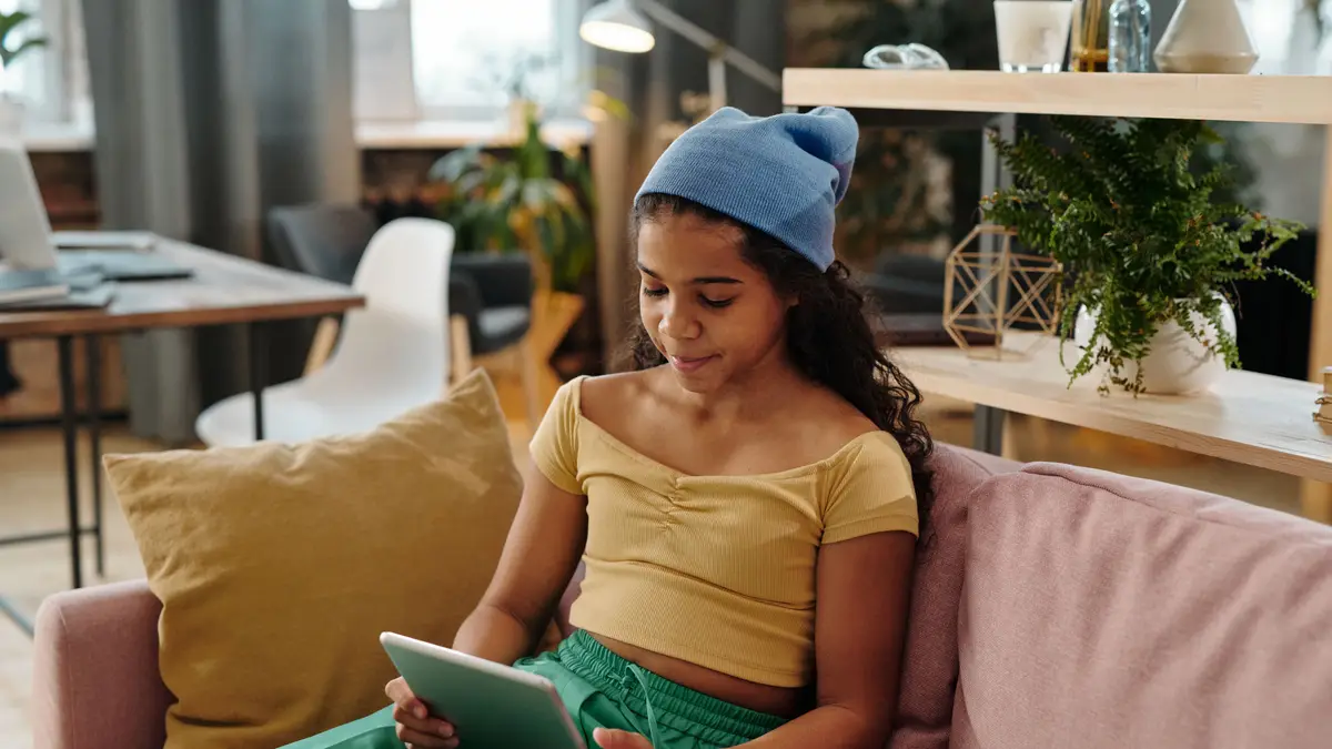 Adolescente assise dans un canapé de salon, une tablette en main