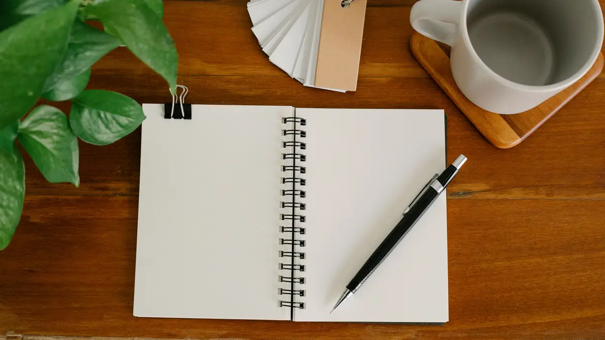Carnet ouvert, crayon et plante sur un bureau en bois
