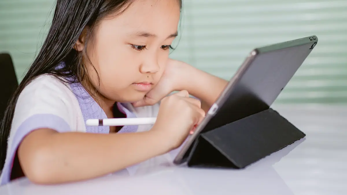 Fillette dessinant au stylet sur une tablette posée sur son support