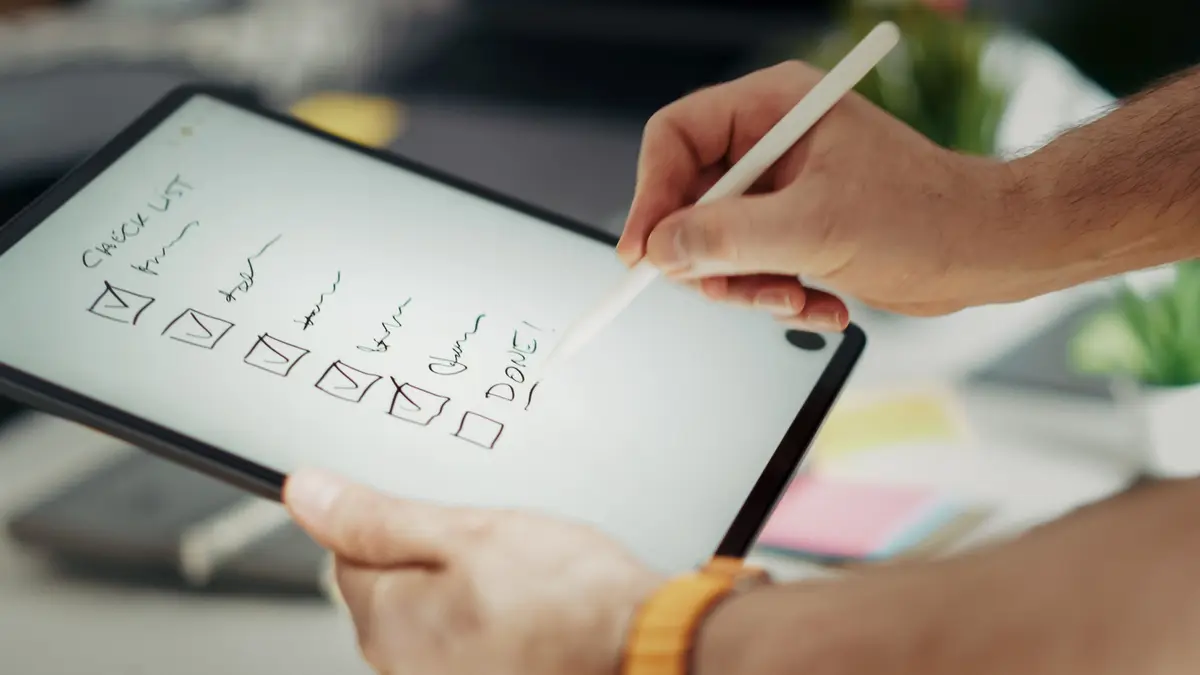 Mains cochant une liste au stylet sur l'écran d'une tablette
