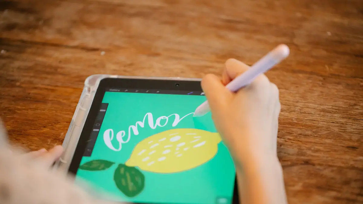 Lettrage au stylet sur une tablette posée sur une table en bois