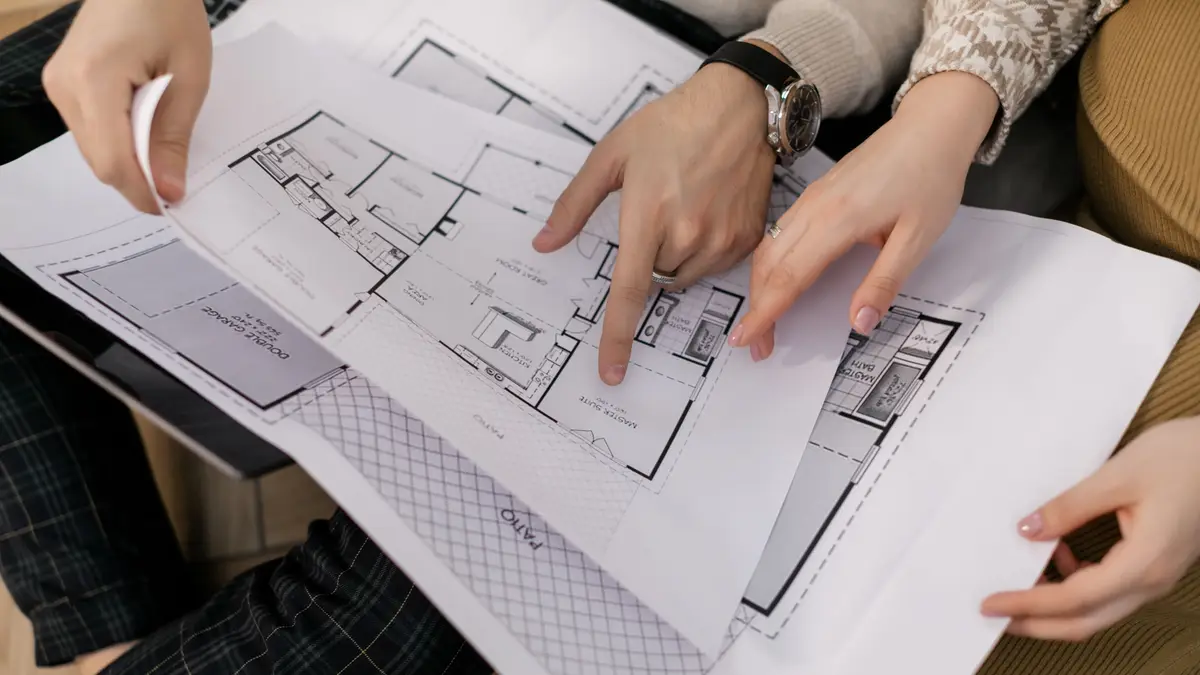 Deux personnes désignant une pièce sur un plan d'architecte
