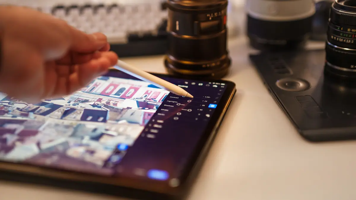 Retouche de photos au stylet sur une tablette, entre des objectifs d'appareil photo