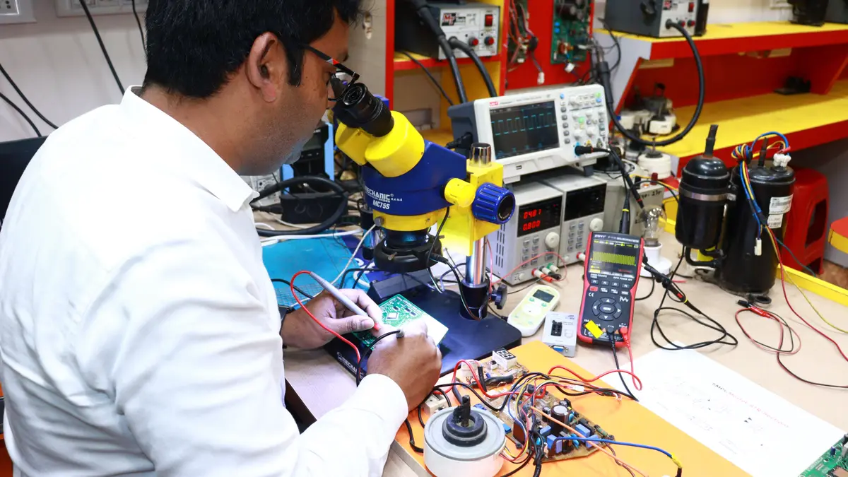 Technicien réparant un appareil électronique à son établi, sous une loupe